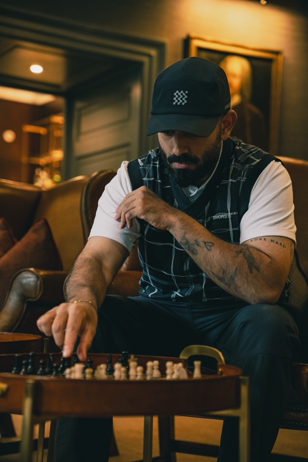 Man in a flat cap studying a chess board, used to preview the grade